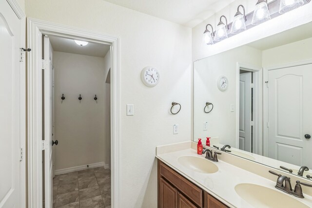 bathroom with double vanity, a sink, and baseboards