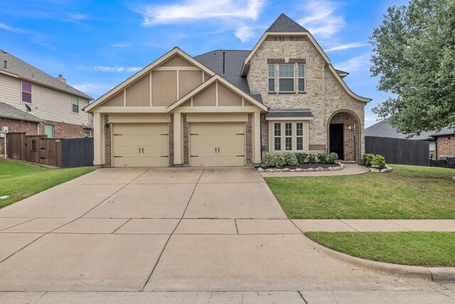 view of front of house with fence, an attached garage, a front lawn, stone siding, and driveway