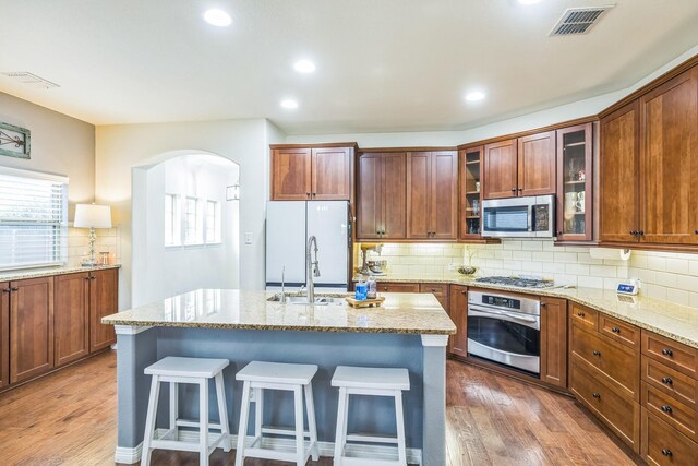 kitchen featuring arched walkways, light stone countertops, stainless steel appliances, and visible vents