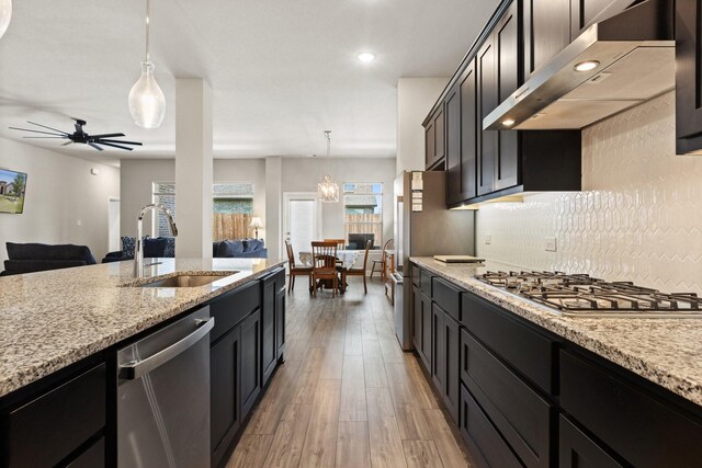 kitchen featuring ceiling fan, under cabinet range hood, a sink, appliances with stainless steel finishes, and decorative light fixtures