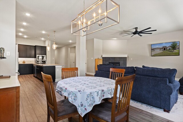 dining area featuring recessed lighting, light wood finished floors, ceiling fan, and a tile fireplace