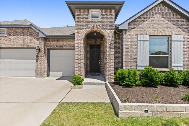 view of front of home featuring brick siding, an attached garage, roof with shingles, and driveway