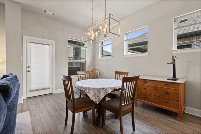 dining room with baseboards, visible vents, wood finished floors, and an inviting chandelier