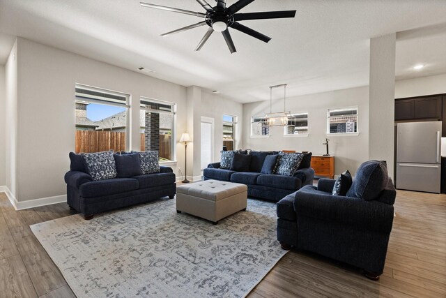 living room with baseboards, ceiling fan, visible vents, and wood finished floors