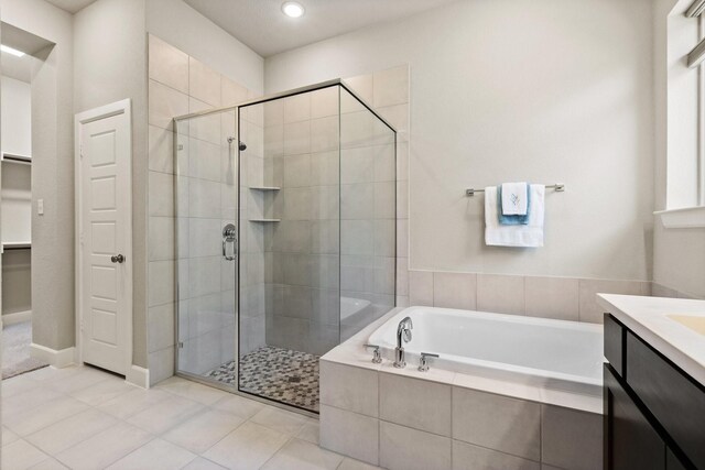 full bathroom featuring vanity, tile patterned flooring, a bath, and a shower stall
