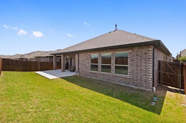back of property with a yard, brick siding, a patio, and a fenced backyard