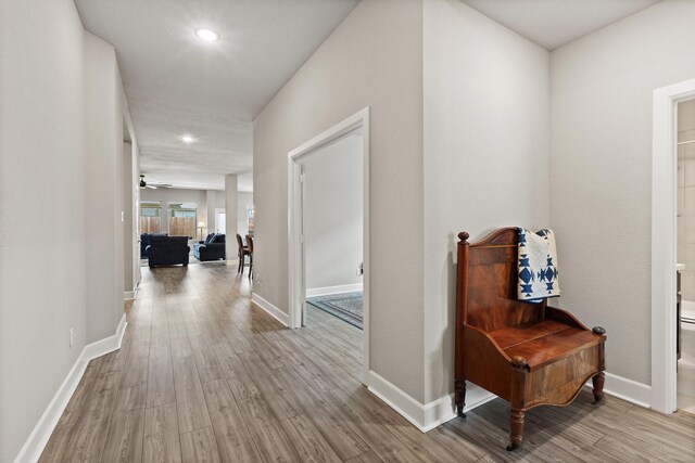 corridor featuring baseboards, recessed lighting, and wood finished floors