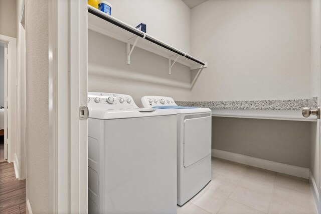 laundry area with baseboards, light tile patterned flooring, laundry area, and washer and clothes dryer