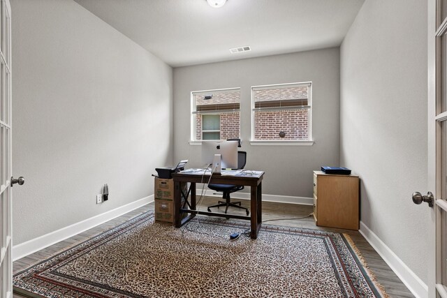 office space featuring baseboards, visible vents, and wood finished floors