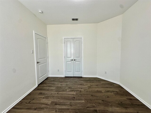 empty room with baseboards, dark wood-style floors, and visible vents
