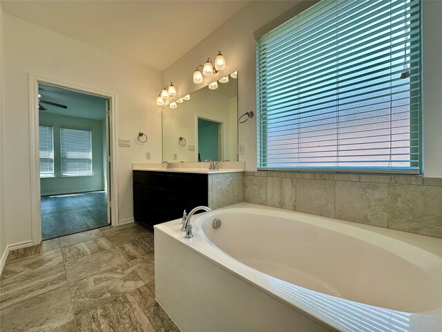 bathroom with double vanity, baseboards, a bath, and a sink