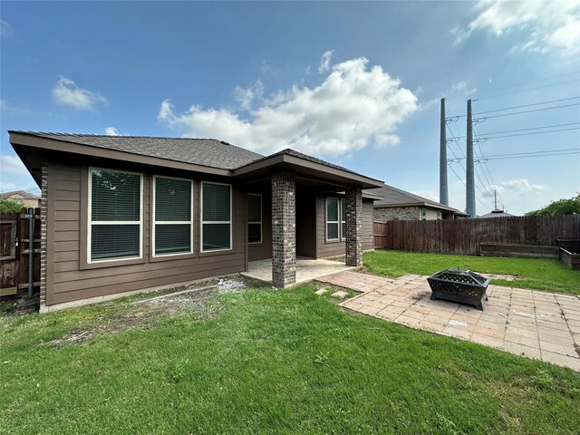 back of house with a fenced backyard, a yard, a fire pit, and a patio area