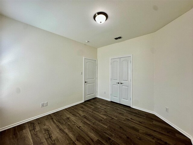 unfurnished room featuring baseboards, visible vents, and dark wood-type flooring