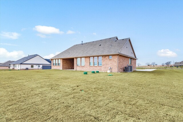 149 Highgate Ct, Boyd, TX 76023 - back of house featuring central air condition unit, brick siding, a yard, and board and batten siding
