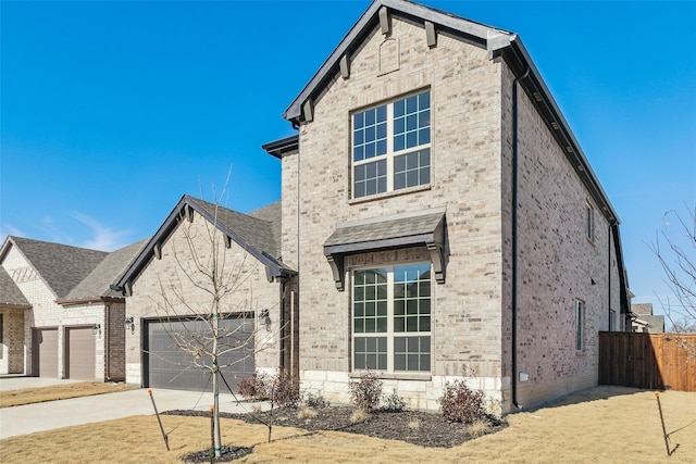 view of front facade featuring fence, concrete driveway, and brick siding