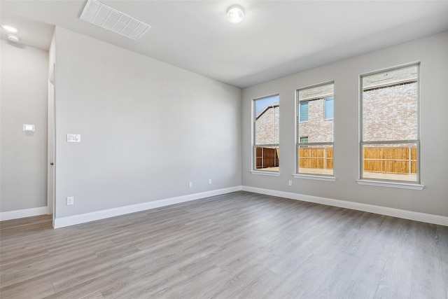 spare room with baseboards, visible vents, and wood finished floors