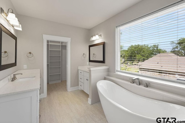 12090 Hackberry Holw, Tyler, TX 75706 - full bath featuring a freestanding bath, a sink, a walk in closet, baseboards, and two vanities