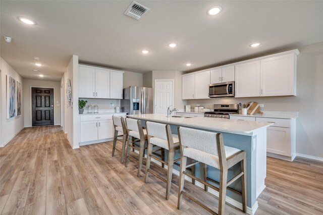 kitchen with a breakfast bar, light wood-style floors, light countertops, stainless steel appliances, and baseboards