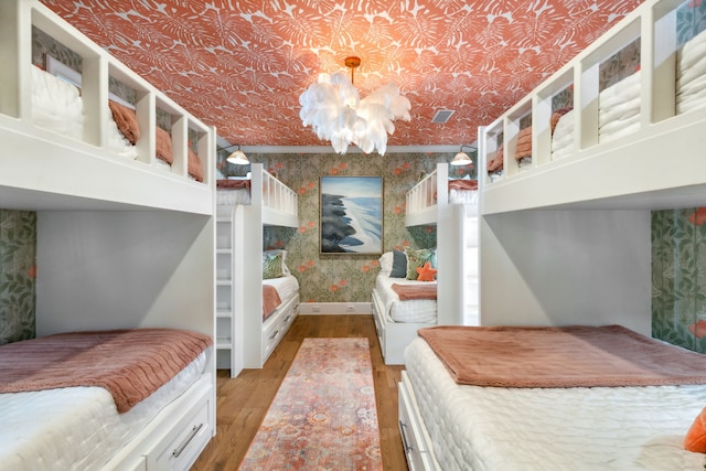bedroom with visible vents, baseboards, an ornate ceiling, wallpapered walls, and light wood-style flooring