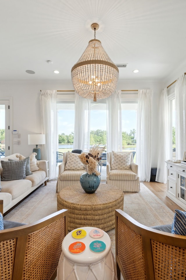 interior space featuring an inviting chandelier, light wood finished floors, a wealth of natural light, and visible vents