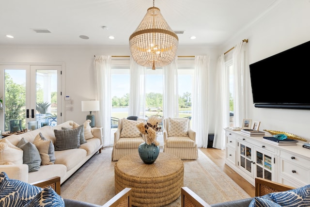 living room with visible vents, ornamental molding, light wood-type flooring, and a chandelier