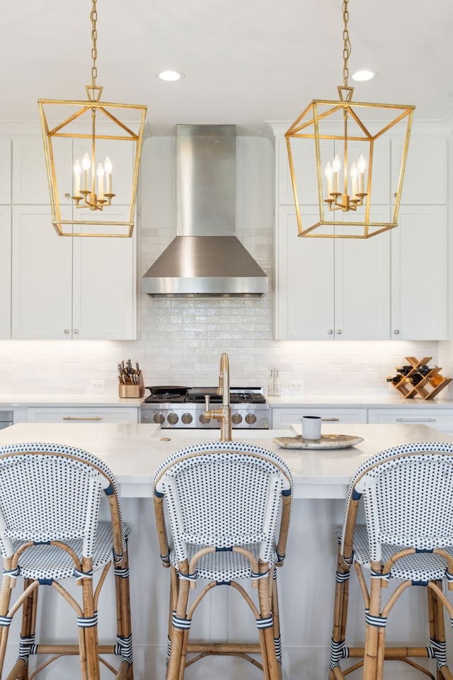 kitchen featuring wall chimney exhaust hood, white cabinets, a notable chandelier, and tasteful backsplash