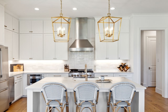kitchen featuring wall chimney range hood, light countertops, stove, and a chandelier