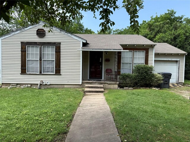 ranch-style house with covered porch, an attached garage, a shingled roof, and a front lawn