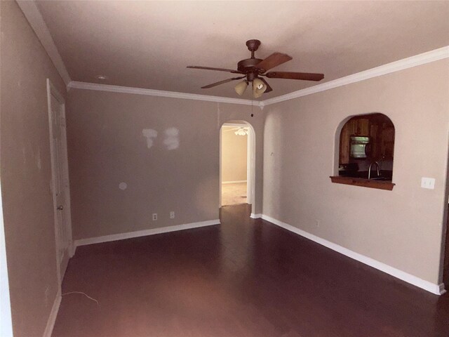 spare room featuring crown molding, arched walkways, a ceiling fan, and baseboards