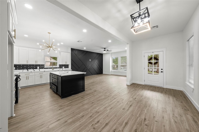 kitchen featuring visible vents, a kitchen island, open floor plan, white cabinetry, and light wood finished floors