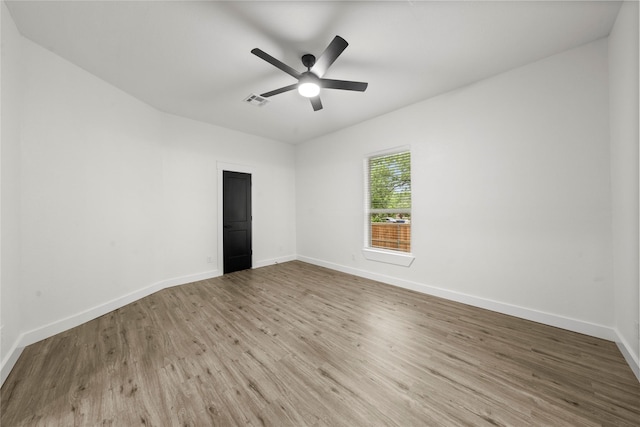 empty room featuring baseboards, a ceiling fan, wood finished floors, and visible vents