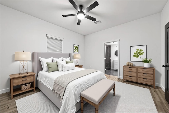 bedroom with ceiling fan, ensuite bath, baseboards, wood finished floors, and visible vents