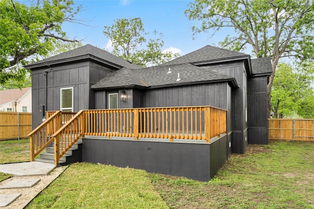 rear view of property featuring a fenced backyard, roof with shingles, and a wooden deck