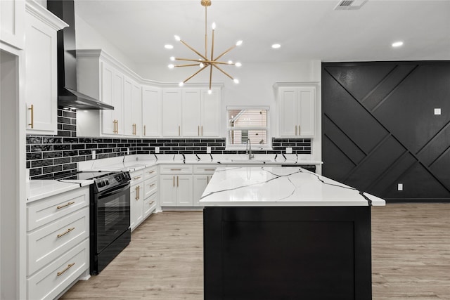 kitchen featuring black electric range, a sink, wall chimney exhaust hood, and light wood finished floors
