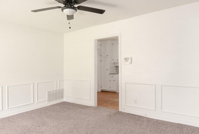 5524 Korth St, Sansom Park, TX 76114 - spare room with carpet flooring, ceiling fan, a decorative wall, a textured ceiling, and wainscoting