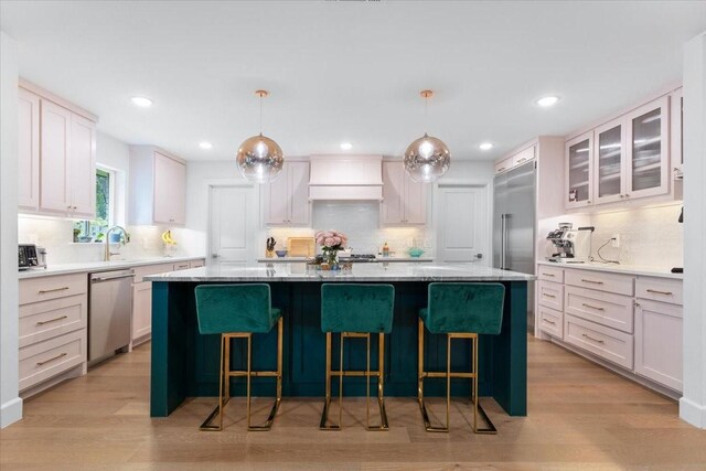 kitchen with a kitchen island, backsplash, premium range hood, and stainless steel appliances