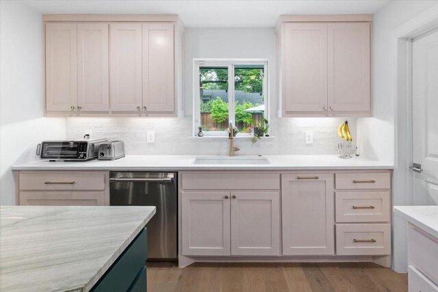 kitchen with a sink, stainless steel dishwasher, backsplash, and light wood-style flooring