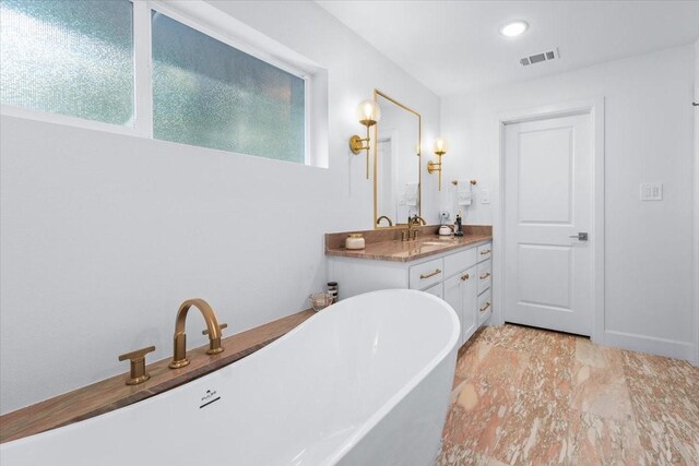 full bath featuring visible vents, vanity, marble finish floor, a freestanding tub, and recessed lighting