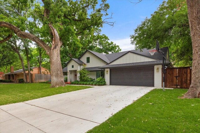 view of front facade featuring fence, an attached garage, a front lawn, board and batten siding, and concrete driveway