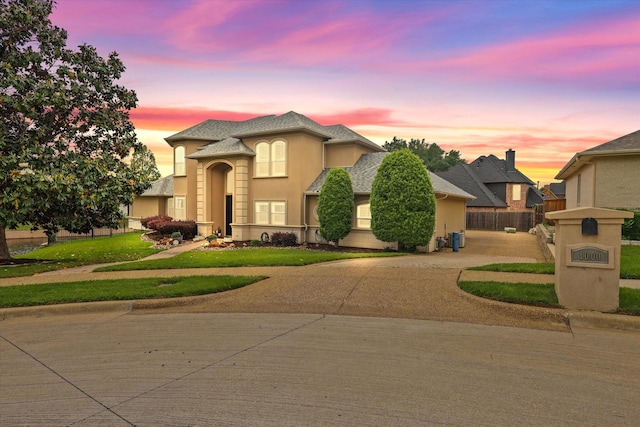 traditional home with fence, stucco siding, and a front lawn