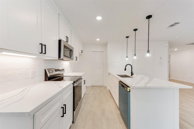 1130 Amsden Cir, Denison, TX 75020 - kitchen featuring appliances with stainless steel finishes, light stone countertops, a sink, white cabinets, and light wood-style flooring