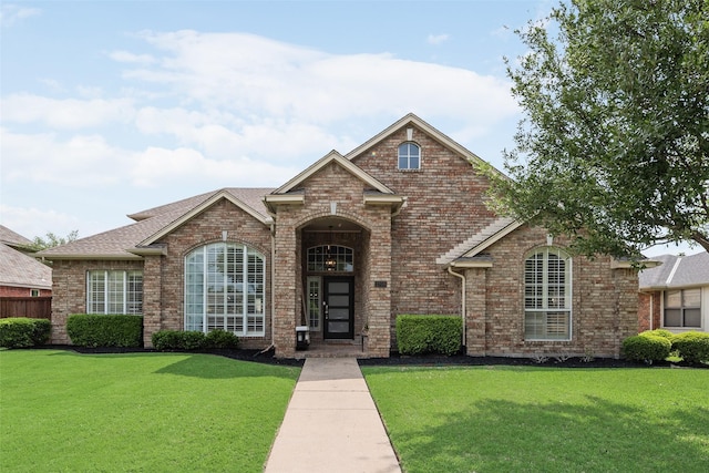 traditional home featuring brick siding, fence, and a front yard