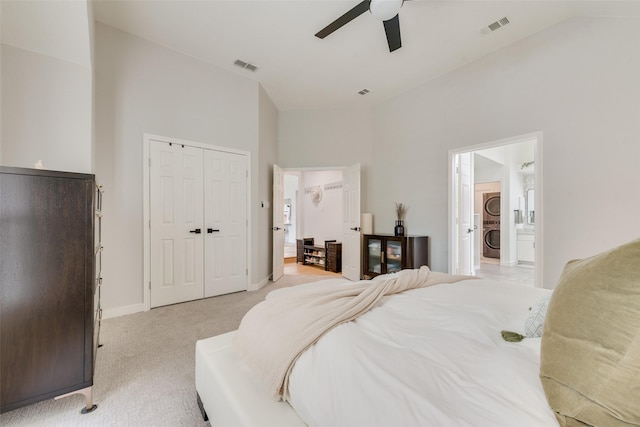 bedroom with light colored carpet, high vaulted ceiling, visible vents, and stacked washer and clothes dryer