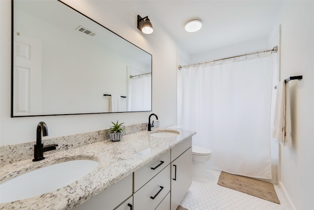 bathroom with double vanity, toilet, visible vents, and a sink