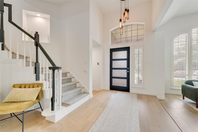 entrance foyer with baseboards, a towering ceiling, wood finished floors, and stairway