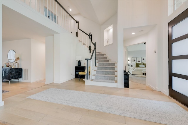 entryway featuring visible vents, a towering ceiling, stairs, wood finished floors, and recessed lighting