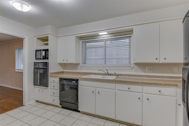 kitchen with a sink, light countertops, black appliances, and white cabinetry