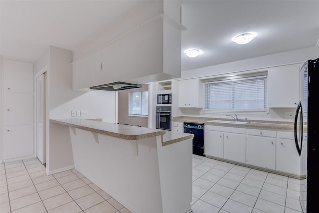 kitchen featuring a peninsula, light tile patterned flooring, a sink, and black appliances