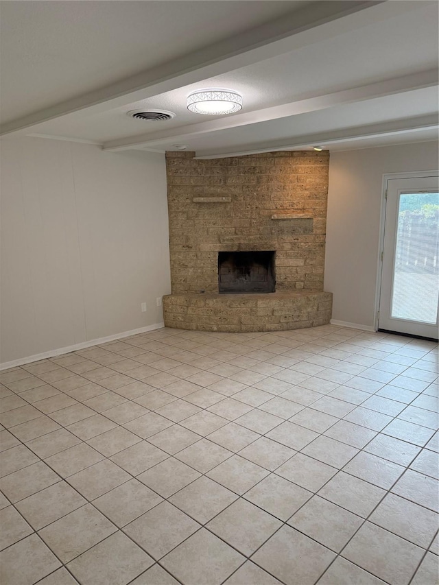 unfurnished living room with beamed ceiling, light tile patterned flooring, a stone fireplace, and visible vents
