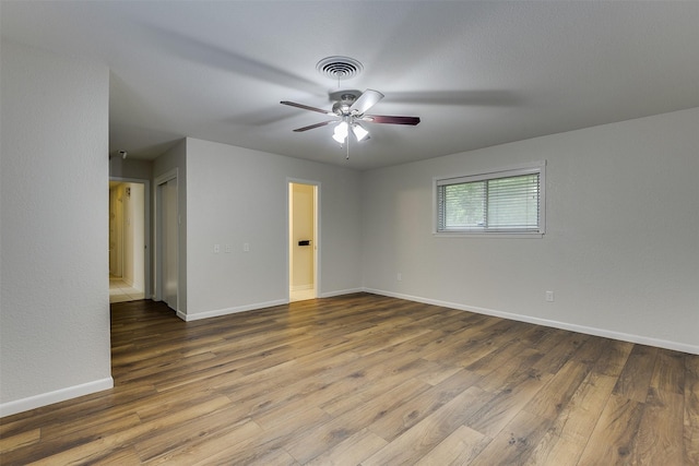 spare room with baseboards, ceiling fan, wood finished floors, and visible vents
